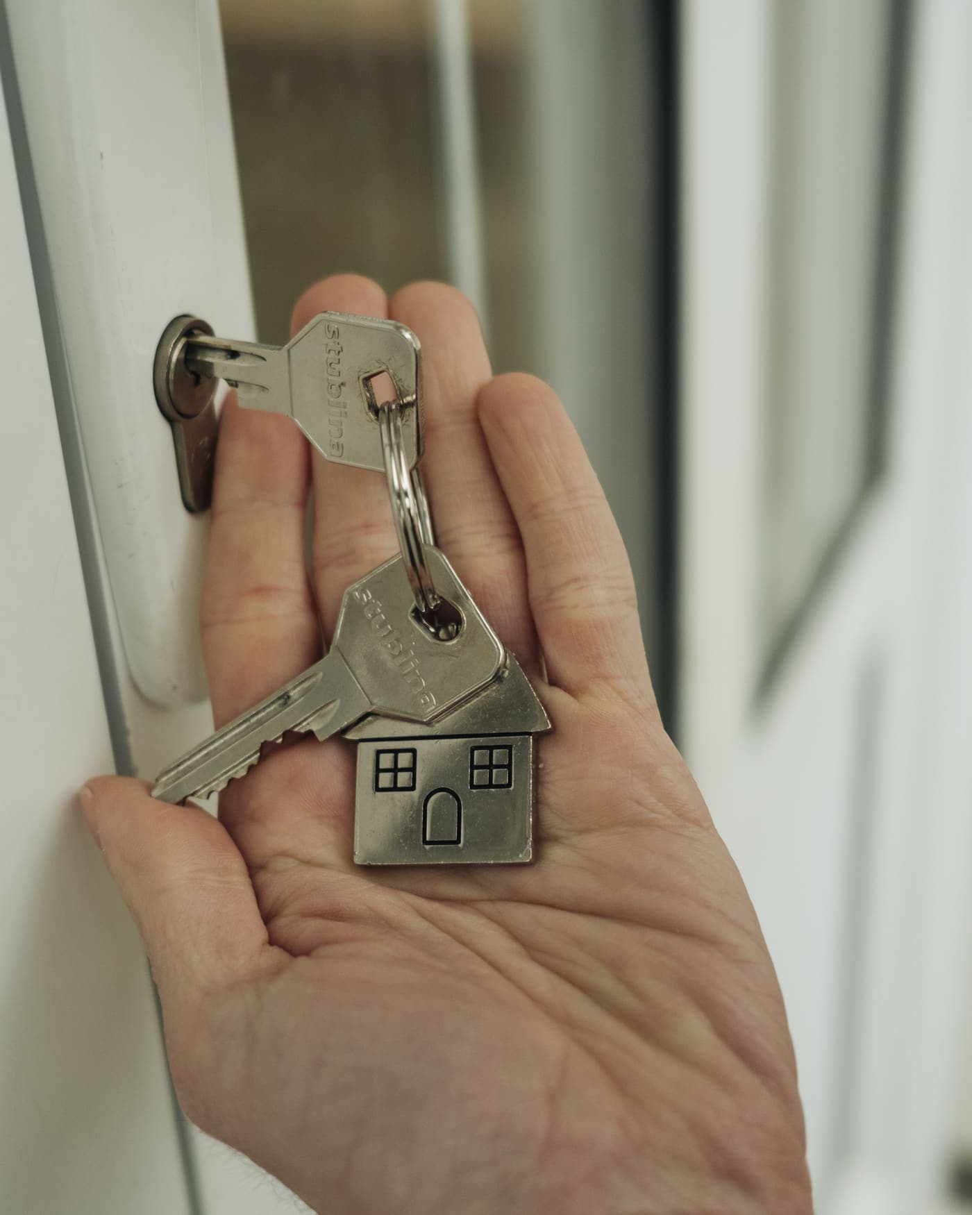Llaves de una casa en la mano, frente a la puerta de entrada